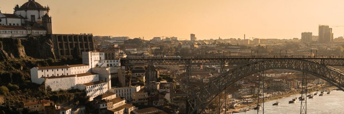 A captivating sunset view of Porto's skyline featuring the iconic Dom Luís I Bridge and riverfront.